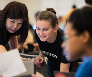 Close up on two employers leaning in to look at a computer.