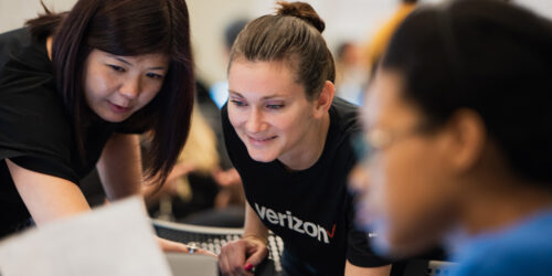 Close up on two employers leaning in to look at a computer.