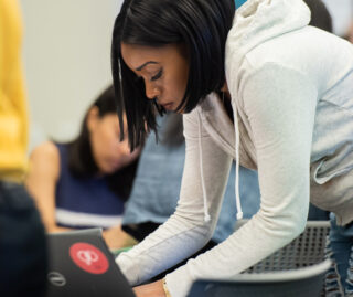 Student standing and leaning over to type on a keyboard.